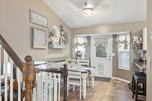 Foyer entrance featuring plenty of natural light, baseboards, stone finish flooring, and stairway