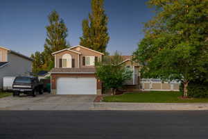 View of front of property with a garage, driveway, and brick siding