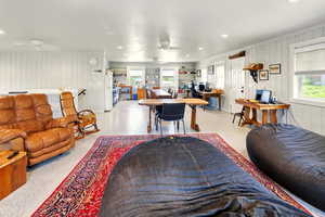 Living room with a desk, ceiling fan, speckled floor, recessed lighting, and wooden walls