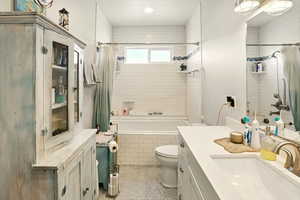 Full bathroom featuring tiled shower / bath, vanity, toilet, and speckle patterned floor