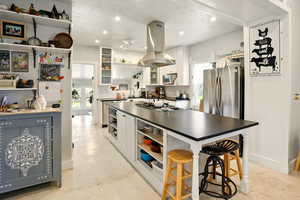 Kitchen with island exhaust hood, open shelves, appliances with stainless steel finishes, a ceiling fan, and dark countertops