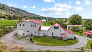 Back of property with dirt driveway, a mountain view, metal roof, a lawn, and a garage