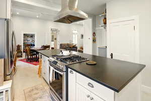Kitchen with appliances with stainless steel finishes, island exhaust hood, dark countertops, white cabinets, and a ceiling fan