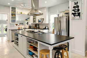 Kitchen with open shelves, dark countertops, island range hood, appliances with stainless steel finishes, and tasteful backsplash