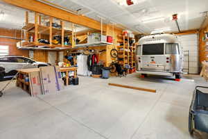 Garage featuring freestanding refrigerator, wooden walls, and ceiling fan