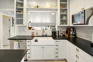 Kitchen with stainless steel appliances, a sink, tasteful backsplash, and dark countertops