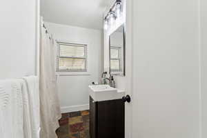 Bathroom with vanity, baseboards, and stone finish floors