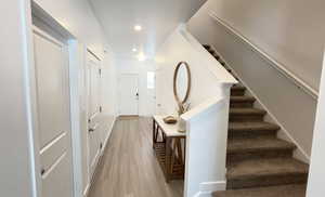 Foyer entrance featuring light wood-type flooring, stairs, recessed lighting, and baseboards