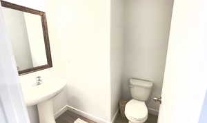 Half bath with wood finished floors, toilet, and baseboards