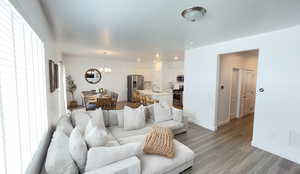 Living room featuring a chandelier, light wood finished floors, baseboards, and recessed lighting
