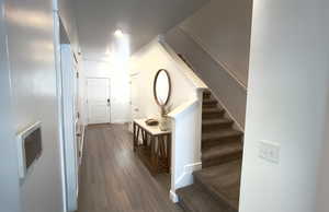 Corridor featuring dark wood-style flooring, stairs, heating unit, and baseboards
