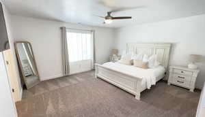 Bedroom featuring dark colored carpet, ceiling fan, and baseboards