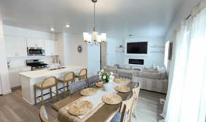 Dining area featuring a chandelier, light wood-style flooring, recessed lighting, and a glass covered fireplace