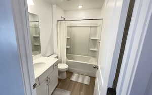 Full bath featuring vanity, wood finished floors, shower / tub combo, and toilet