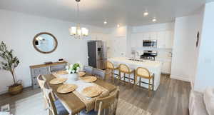 Dining space with light wood-style floors, a chandelier, recessed lighting, and baseboards