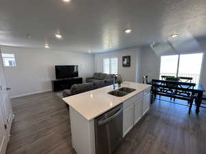 Kitchen with a sink, dishwasher, dark wood-type flooring, a center island with sink, and recessed lighting
