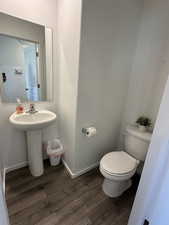 Bathroom with wood finished floors, toilet, and baseboards