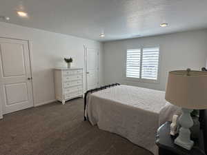 Bedroom featuring dark carpet, a textured ceiling, recessed lighting, and baseboards
