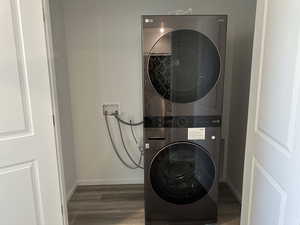 Laundry room featuring estacked washer and dryer, wood finished floors, and baseboards