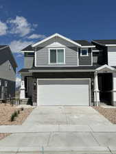 View of front of home with driveway, an attached garage, and stone siding