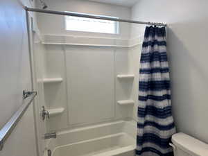 Bathroom with shower / bath combination with curtain and toilet