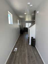Hall with baseboards, dark wood-style flooring, and healthy amount of natural light