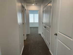 Corridor with dark carpet and baseboards