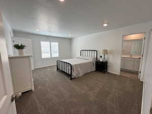 Bedroom featuring dark colored carpet, baseboards, recessed lighting, a sink, and ensuite bathroom