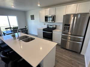 Kitchen with stainless steel appliances, a sink, dark wood-type flooring, light countertops, and a textured ceiling