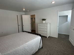 Bedroom featuring a walk in closet, dark colored carpet, a closet, recessed lighting, and baseboards