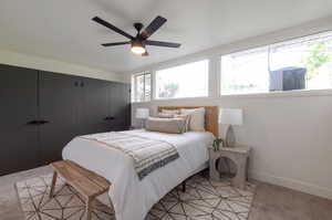 Bedroom featuring light colored carpet, baseboards, and ceiling fan