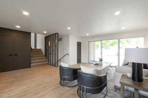 Dining area with light wood-style floors, recessed lighting, and stairs