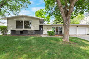 Split level home featuring an attached garage, driveway, and a front lawn