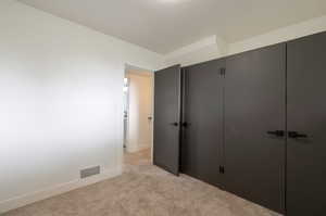 Unfurnished bedroom featuring light carpet, baseboards, and a closet