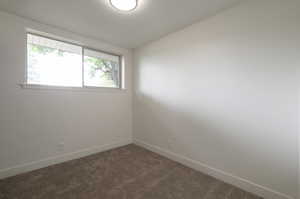 Unfurnished room featuring dark carpet and baseboards