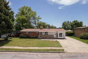 Ranch-style house with concrete driveway and a front lawn
