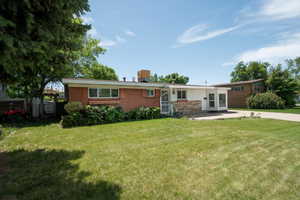 View of front of house featuring a front lawn, brick siding, and a patio