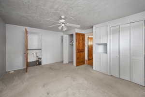 Unfurnished bedroom with multiple closets, carpet flooring, ensuite bath, and ceiling fan
