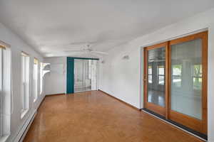 Spare room with a baseboard radiator, a ceiling fan, healthy amount of natural light, and baseboards