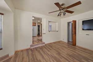 Spare room featuring wood finished floors, baseboards, and a ceiling fan