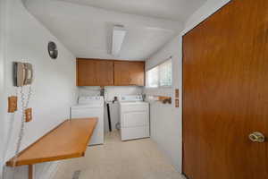 Laundry area featuring cabinet space, washing machine and clothes dryer, light floors, and baseboards