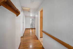 Hallway with light wood finished floors, baseboards, and an upstairs landing