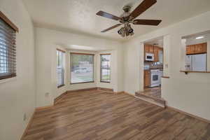 Unfurnished living room with wood finished floors, baseboards, and ceiling fan