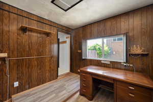 Home office with wooden walls and light wood-style floors