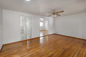 Empty room featuring wood finished floors, a ceiling fan, and baseboards
