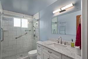 Bathroom featuring vanity, toilet, and a shower stall