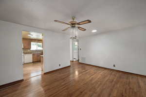 Unfurnished living room featuring wood finished floors, ceiling fan, and baseboards