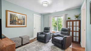 Living area featuring wood finished floors, a textured ceiling, and baseboards