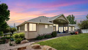 View of front of house with stucco siding, a shingled roof, and a patio