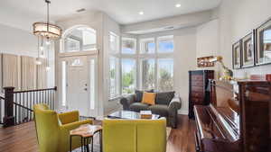 Living room featuring a towering ceiling, wood finished floors, recessed lighting, baseboards, and a chandelier